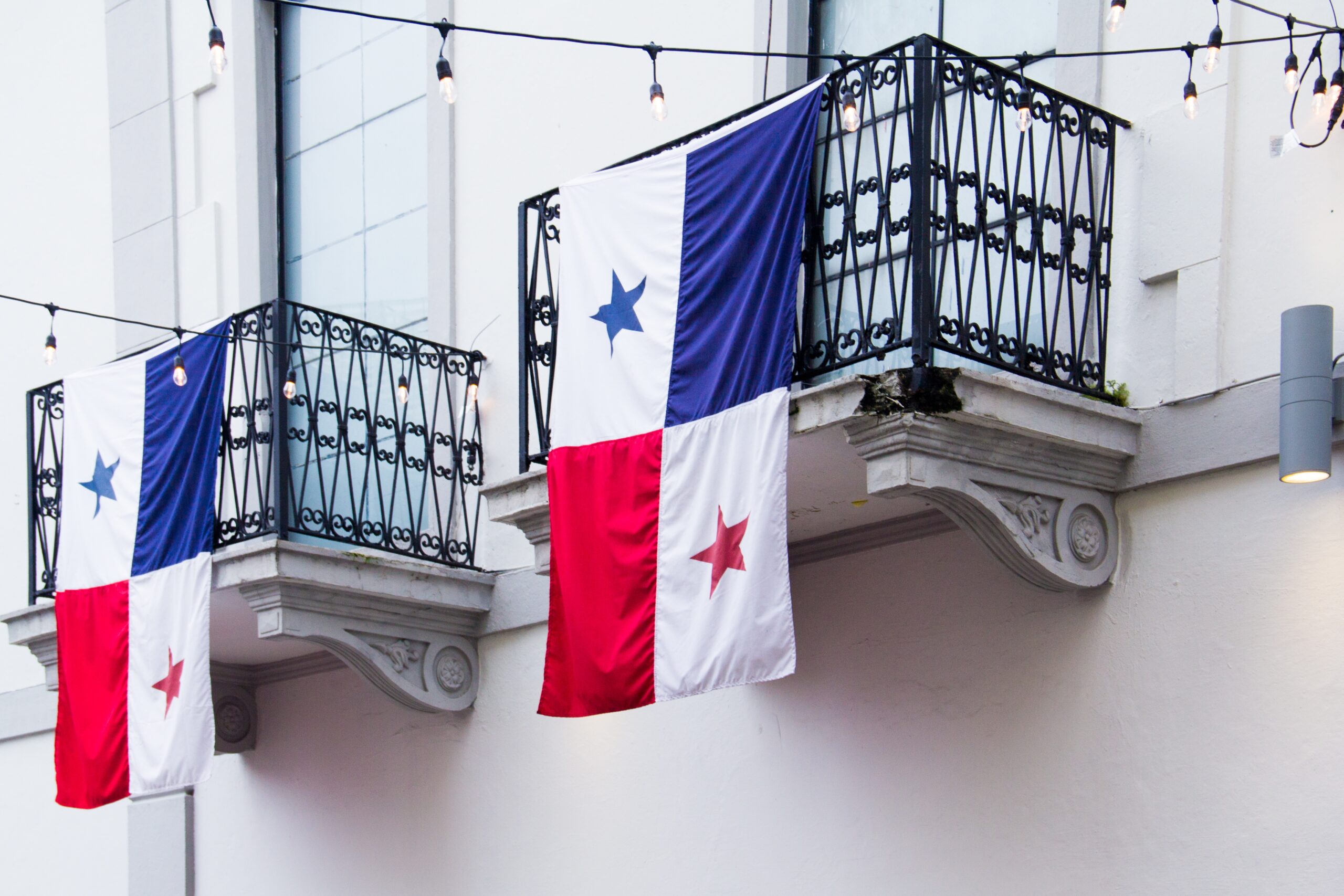 Flags of Panama hanging from the balconies of the houses under the sunlight at daytime