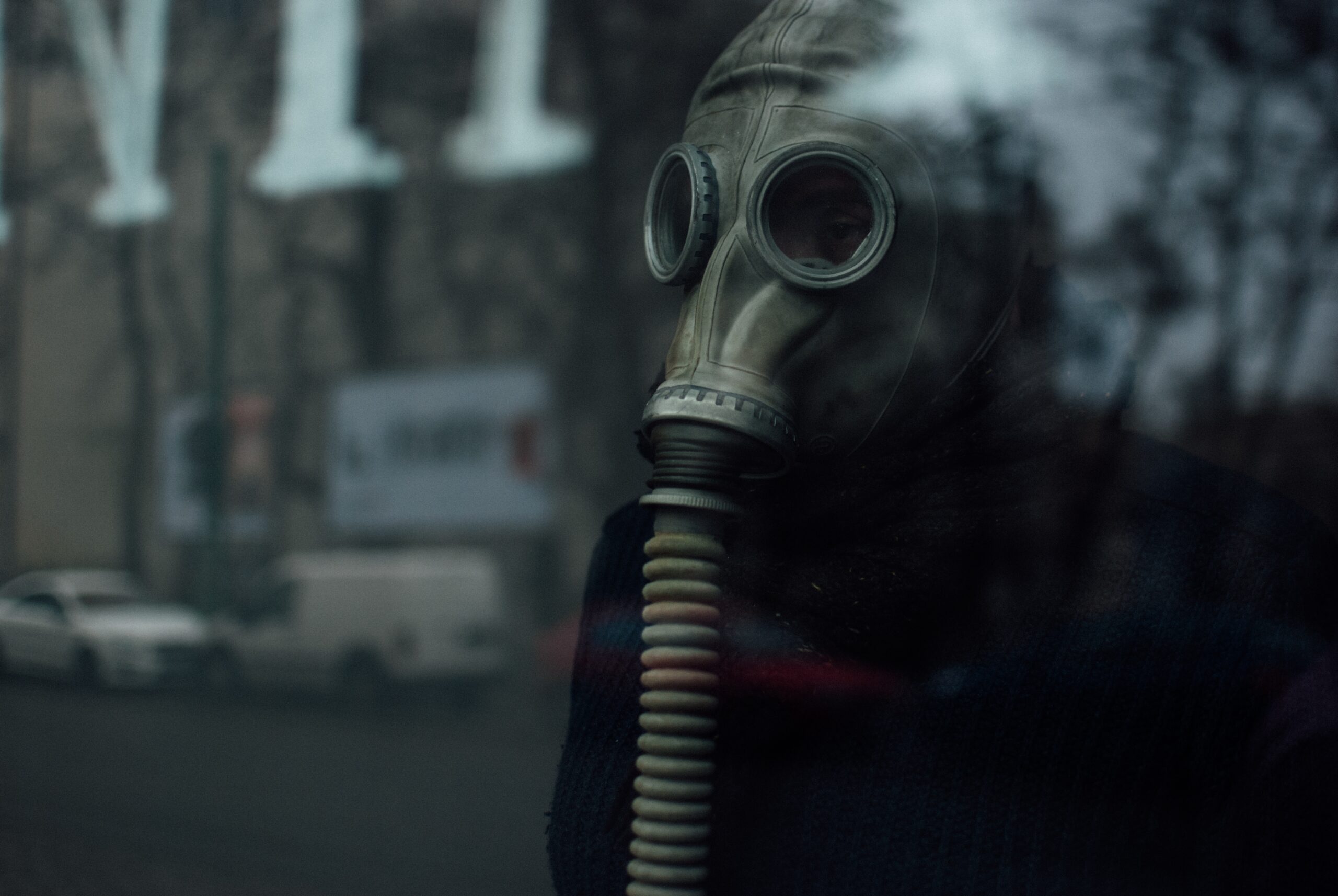 A person wearing a respirator standing behind the glass - air pollution concept