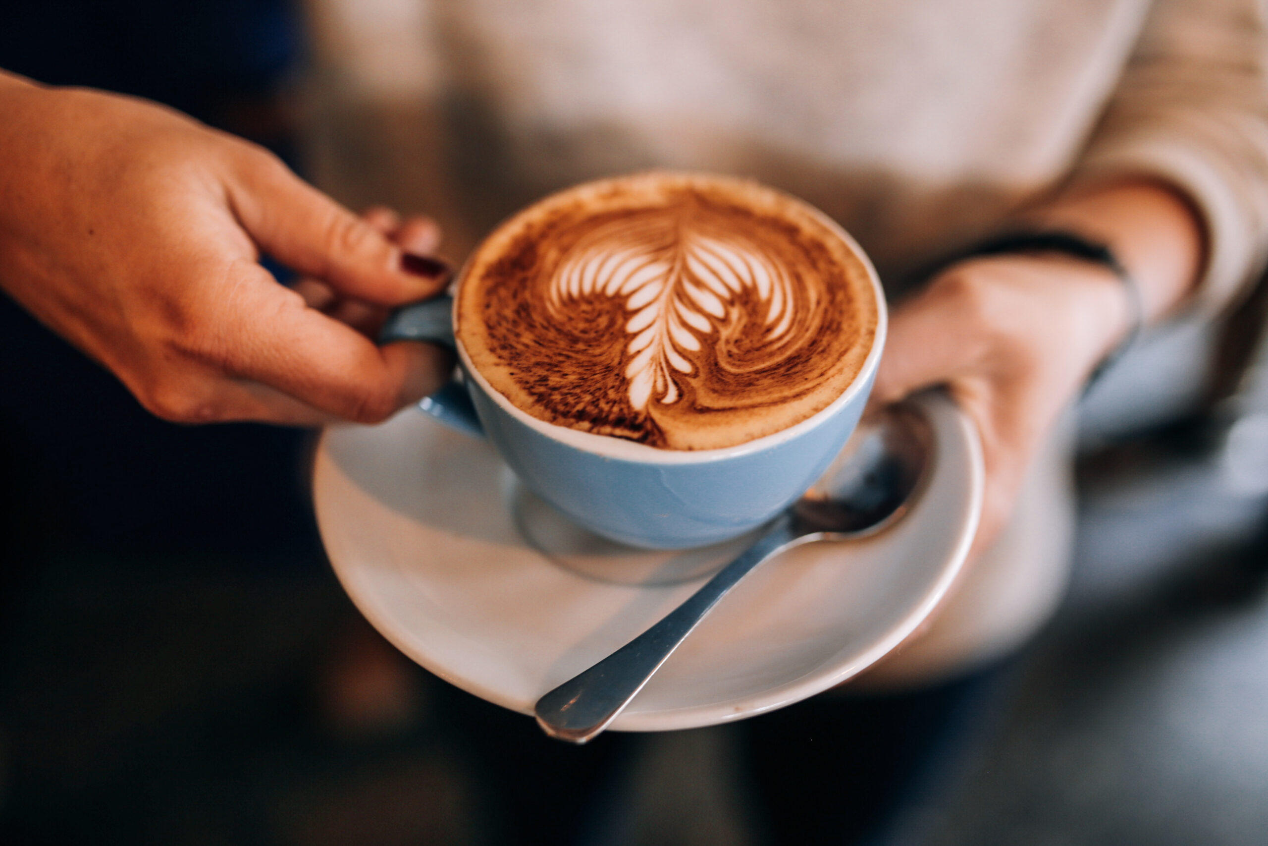 Woman hold cup on plate with hot latte coffee